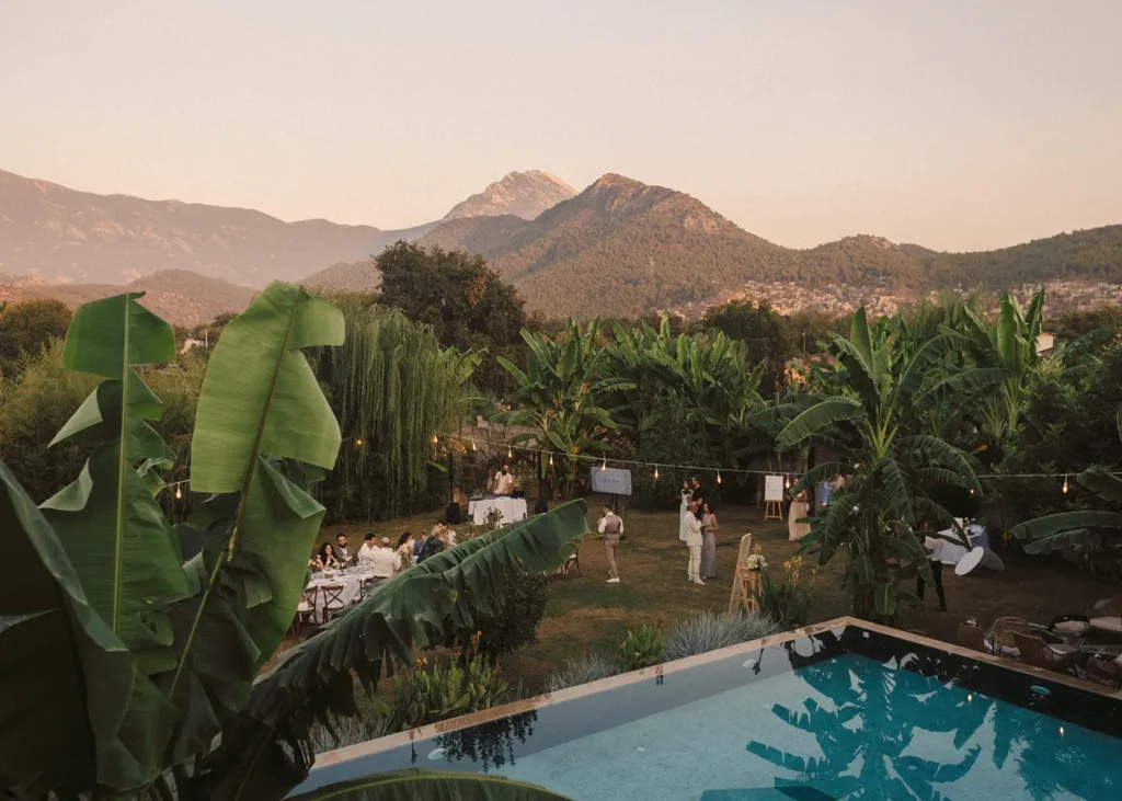 Outdoor bohemian wedding celebration by the pool with mountain views and banana trees at Turunç House in Kayaköy.